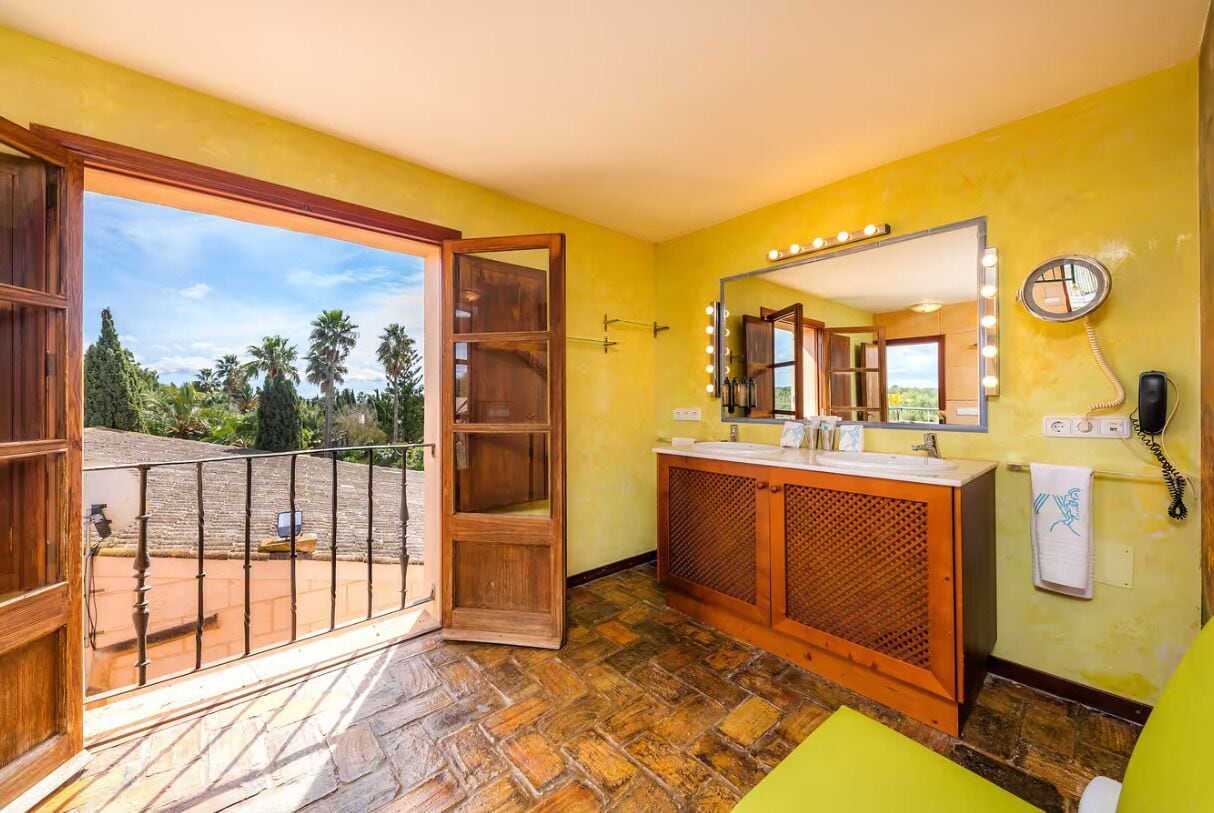 A bathroom with a large mirror, vanity, and a view of the outdoors.