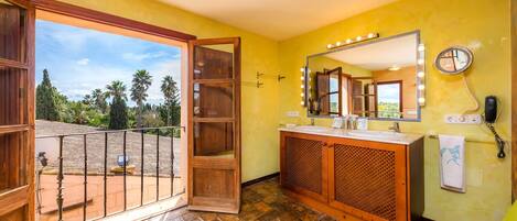 A bathroom with a large mirror, vanity, and a view of the outdoors.