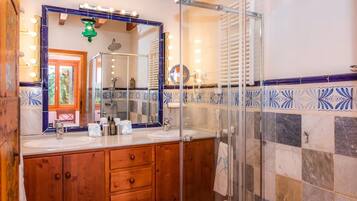 Un baño con dos lavamanos, un espejo grande con iluminación y una ducha, además de azulejos con diseño.
