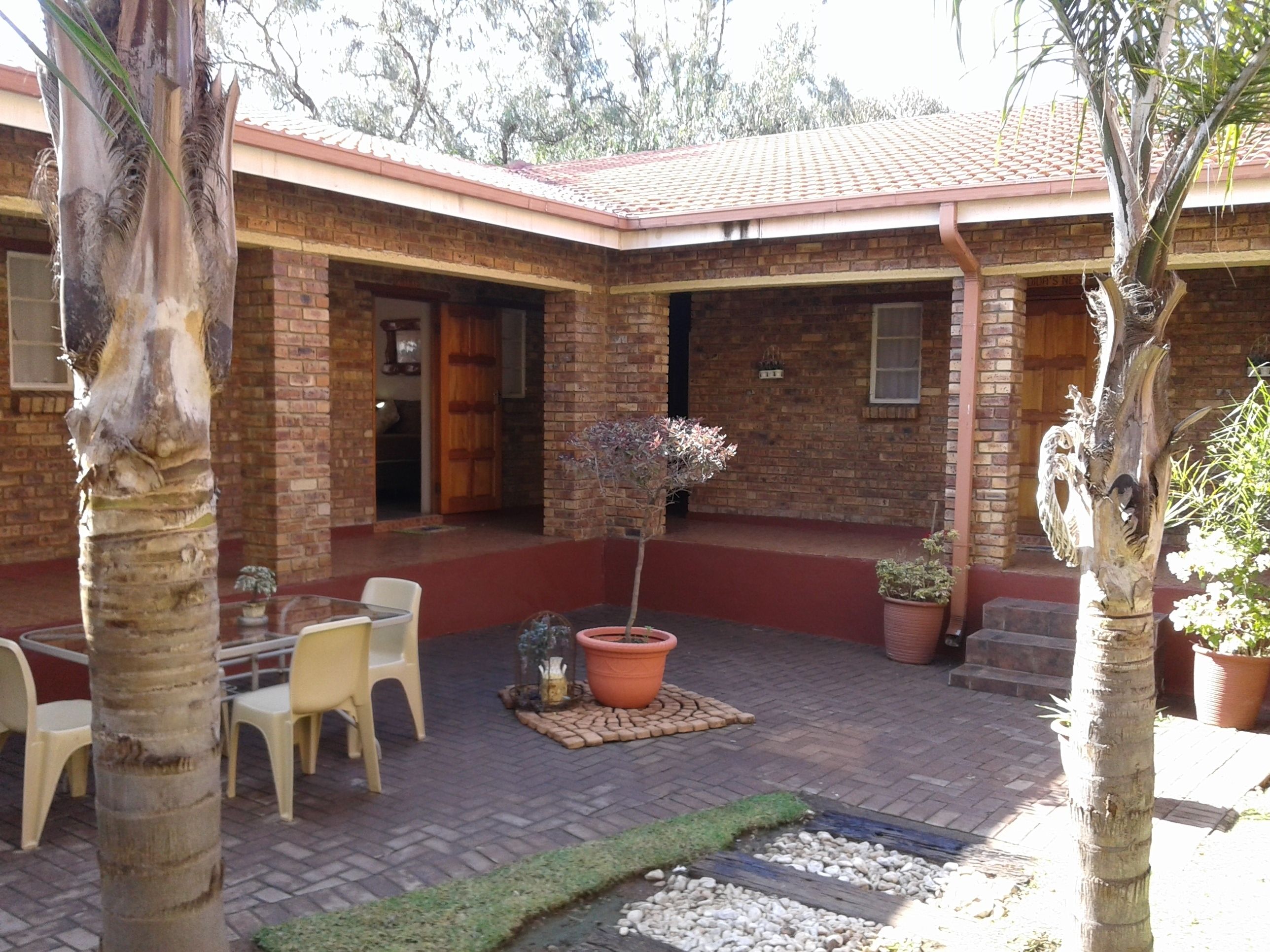 A brick building with a tiled roof, outdoor seating area, and potted plants.