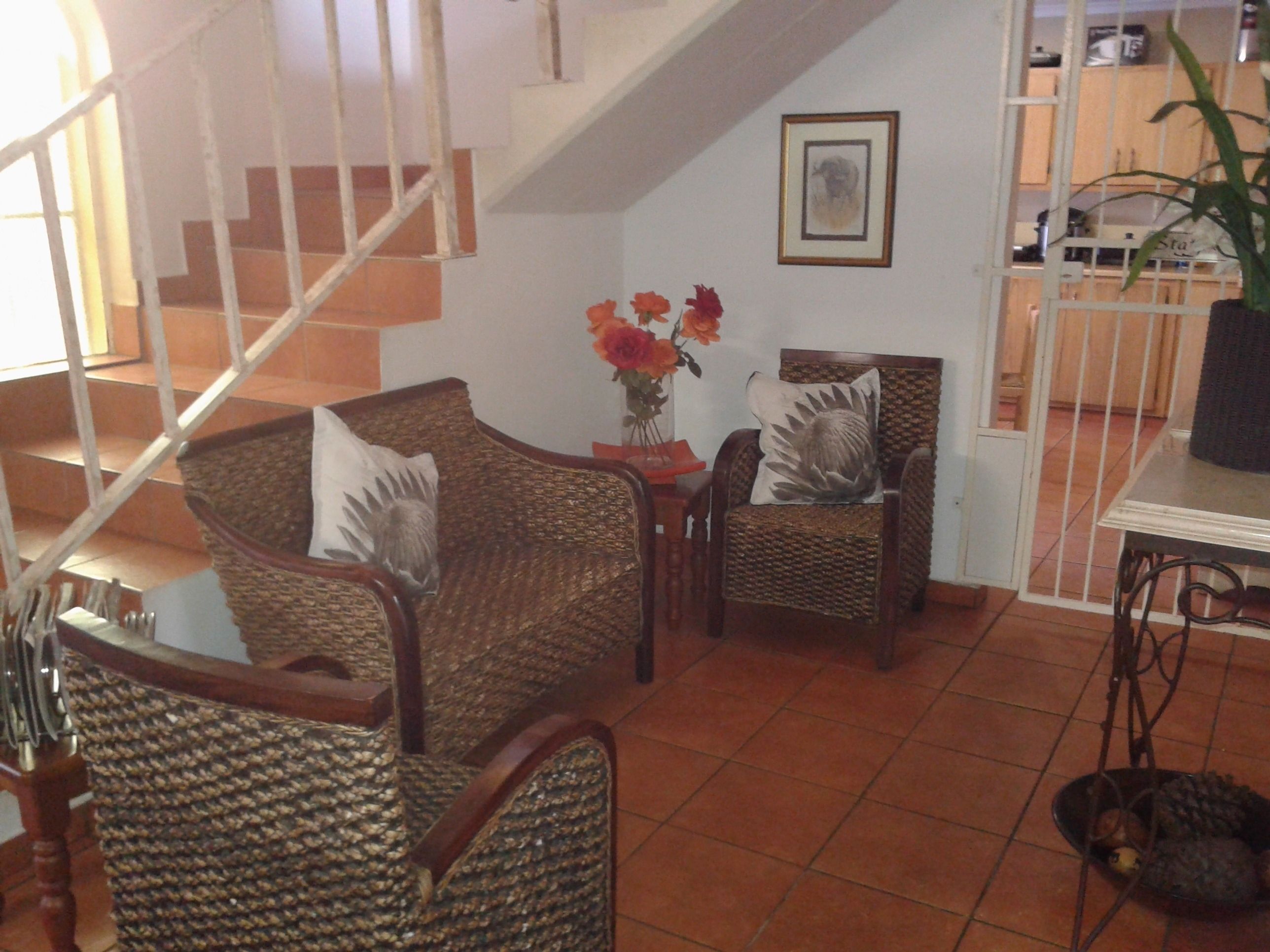 A living room with wicker furniture, a staircase, and a dining area with a table and chairs.