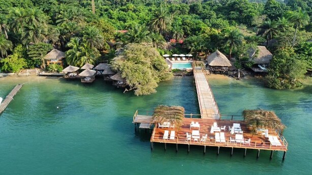 An aerial view of a tropical resort with overwater bungalows, a wooden dock, and a thatched-roof structure. - Ponta Anchaca (Rubane)