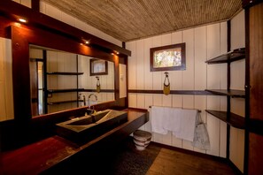 A bathroom with a wooden vanity, a large mirror, a window with a view, and a towel rack.