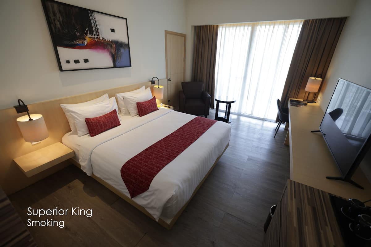 Una habitación de hotel con una cama grande, televisión, escritorio y silla.