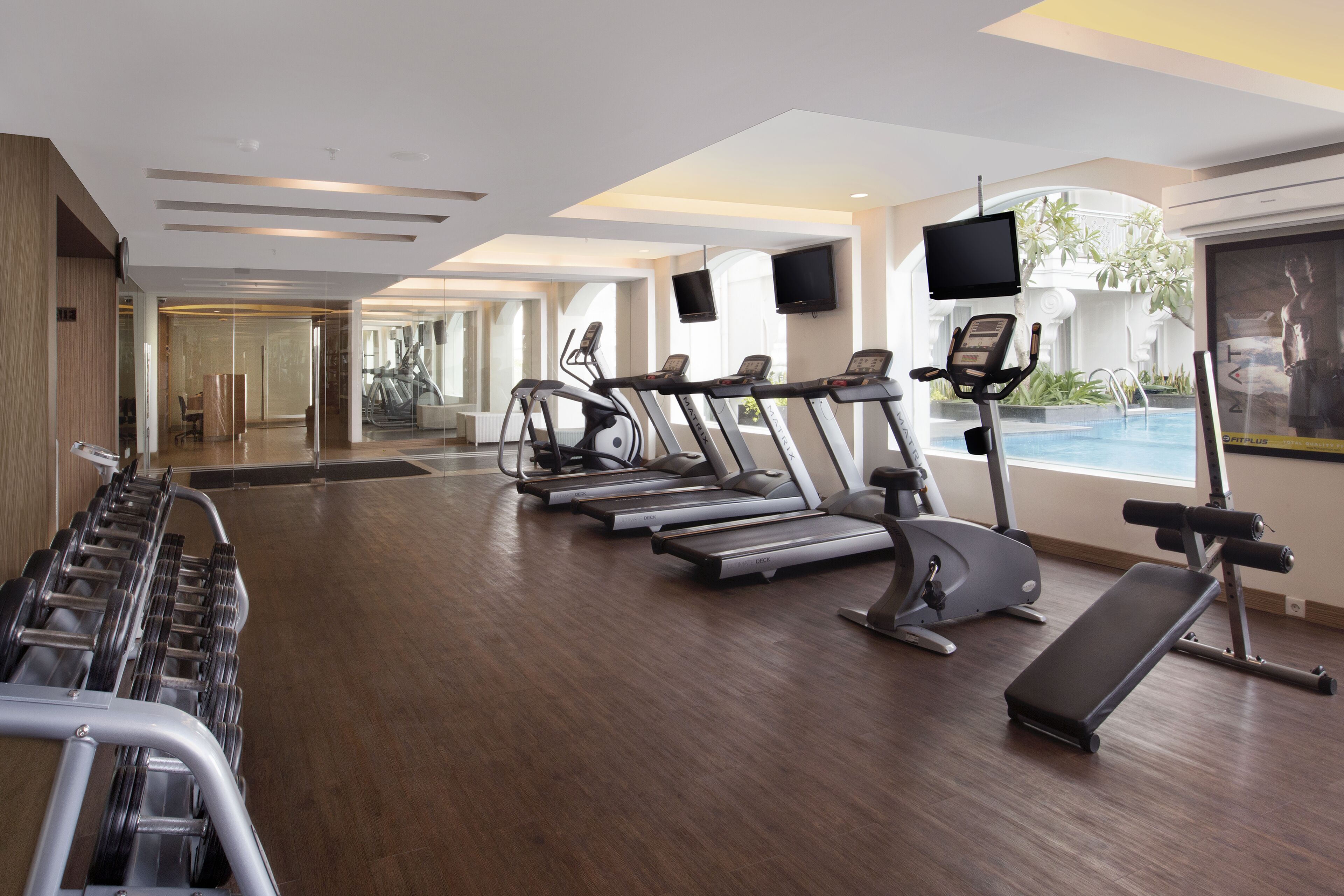 A modern gym with treadmills, ellipticals, and weight machines.