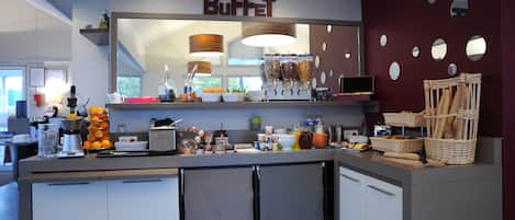 Zona de bufé con mostrador, recipientes de comida y un letrero que dice 'BUFFET'.