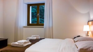 Une chambre d’hôtel avec un lit, une table de chevet, une lampe et une fenêtre avec des rideaux.
