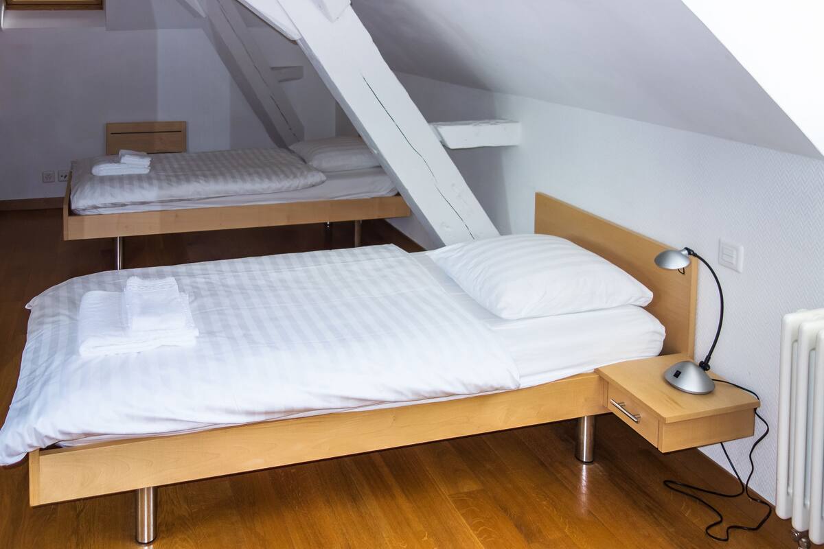 Ein Schlafzimmer mit zwei Betten, Holz-Kopfteilen, einem Nachttisch mit Lampe und einer Heizung.