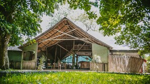A rustic wooden structure with a thatched roof, surrounded by lush greenery and a bamboo fence. - Selous Kinga Lodge (Mloka)