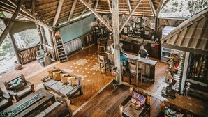 A rustic wooden interior with a high ceiling, a bar area, and a seating area with wooden furniture. - Selous Kinga Lodge (Mloka)