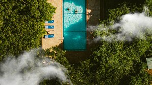 An aerial view of a pool surrounded by lush greenery, with a clear blue sky above. - Selous Kinga Lodge (Mloka)