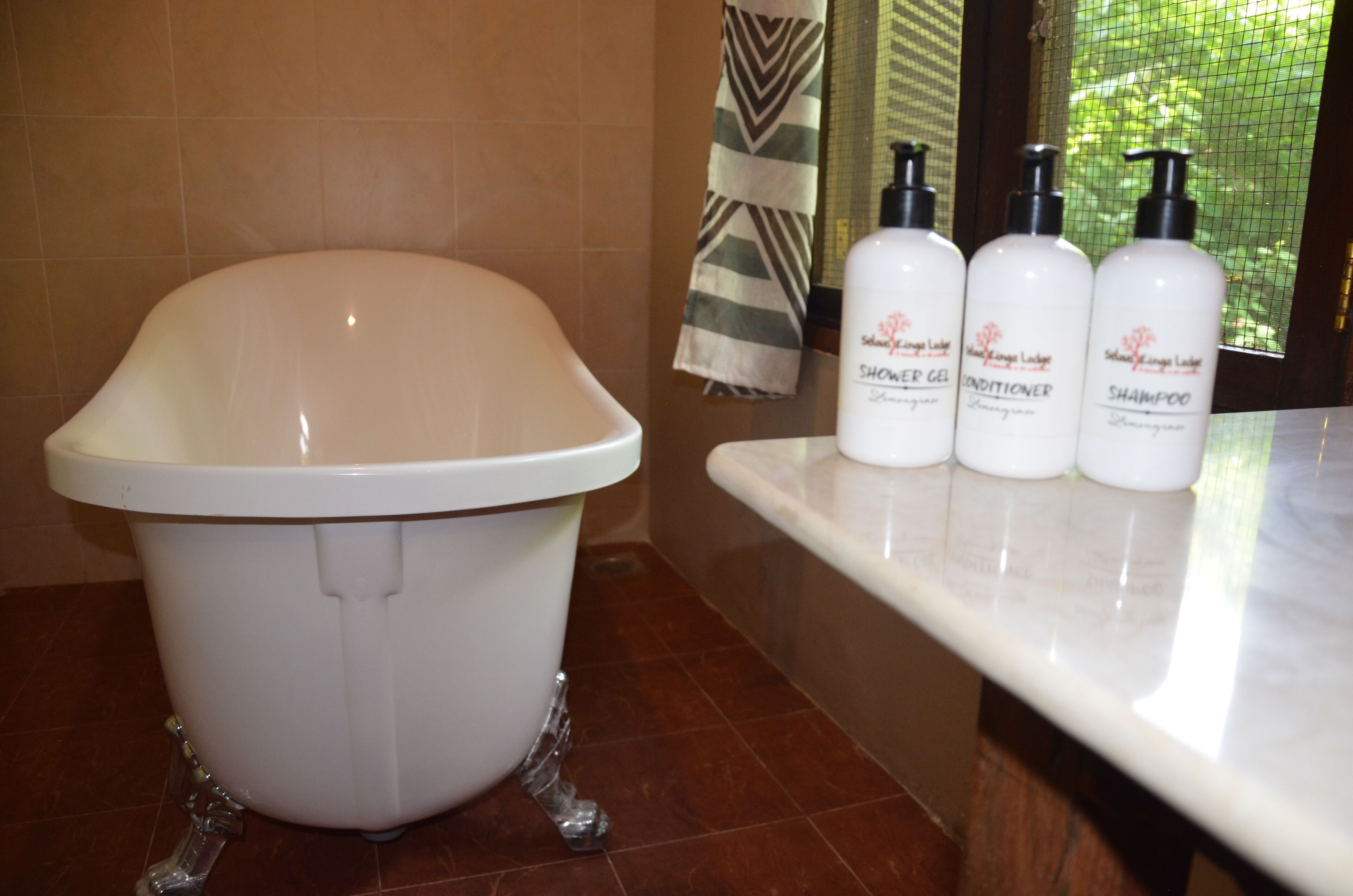 Un baño con una bañera blanca, ducha y estante con tres botellas de champú y acondicionador.