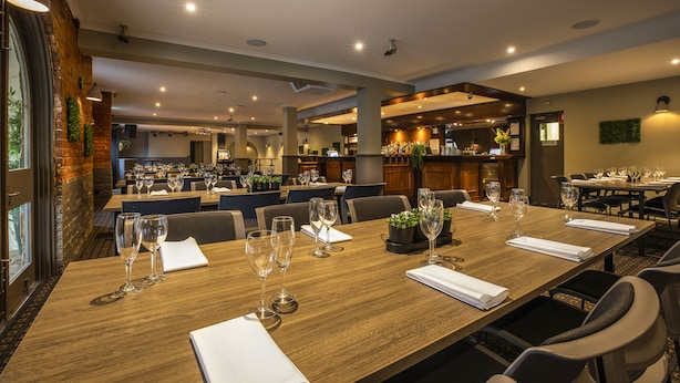 A spacious dining area with multiple tables set for guests, featuring a modern design with wooden tables and comfortable seating. - Nightcap at Ferntree Gully Hotel Motel (Ferntree Gully)