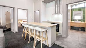 A modern kitchen with a central island, bar stools, and a view into the adjacent living area. - Nightcap at Ferntree Gully Hotel Motel (Ferntree Gully)