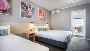 A hotel room with two beds, a nightstand, a desk, and a window.