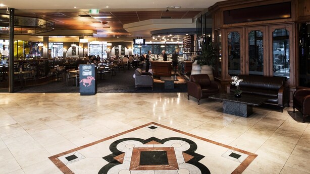 A spacious lobby with a large chandelier, a patterned floor, and a seating area with leather sofas. - Nightcap at Matthew Flinders Hotel (Chadstone)