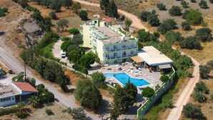 An aerial view of a resort with a swimming pool, multiple buildings, and a road. - Millenium Studios (Rhodes)