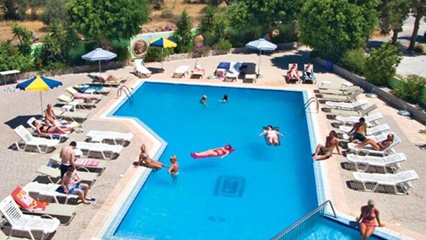 A swimming pool surrounded by sun loungers and umbrellas, with people swimming and relaxing. - Millenium Studios (Rhodes)