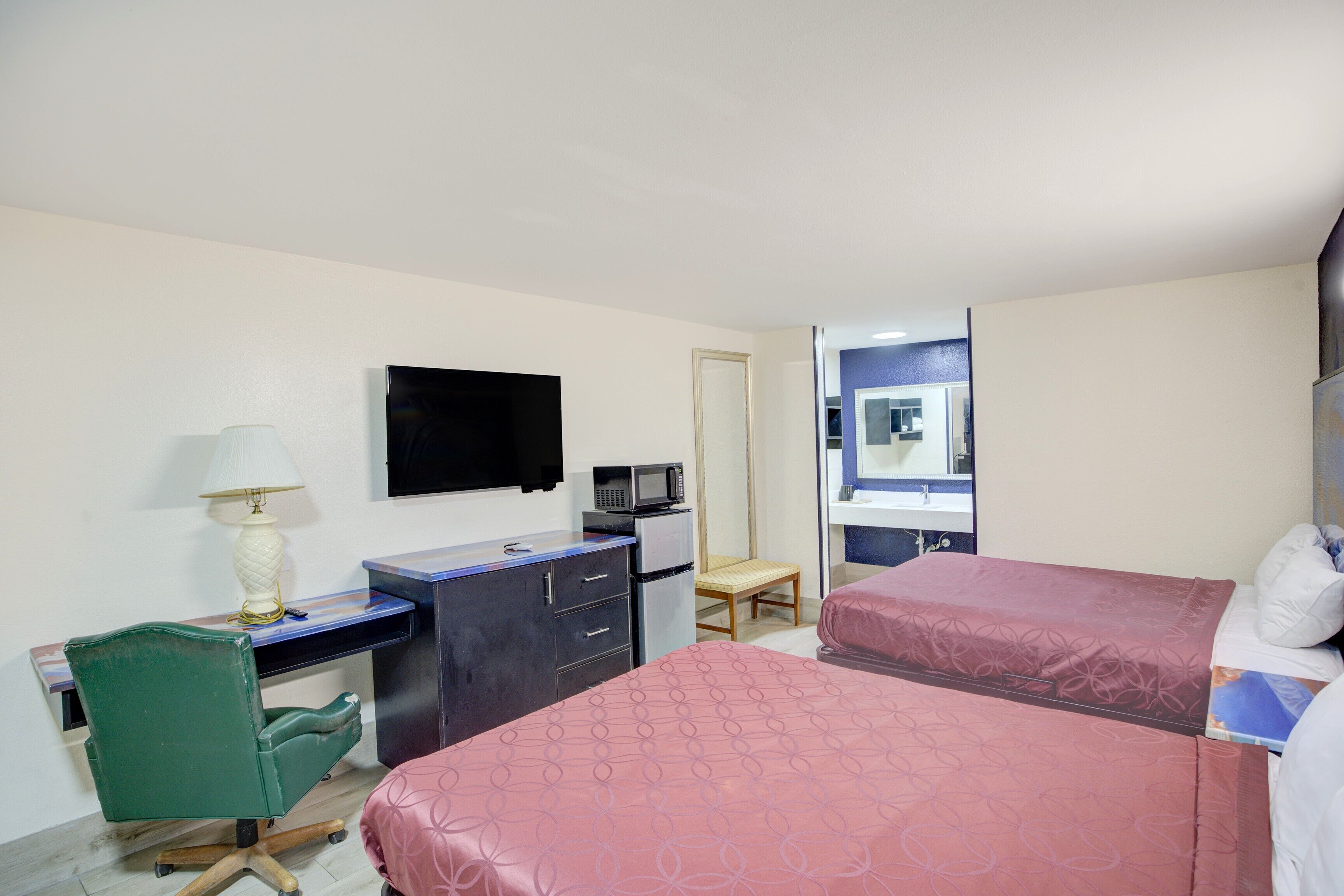 Habitación de hotel con escritorio, televisión, microondas, una silla y dos camas.