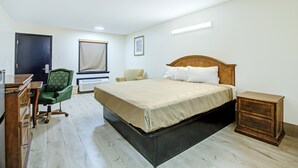 Een slaapkamer met een bed, een bureau, een stoel en een nachtkastje.