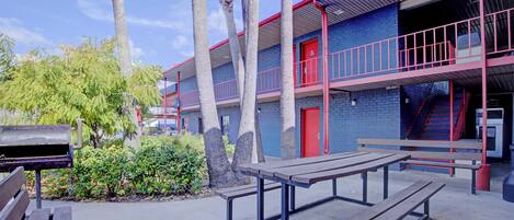 Un edificio con puerta roja, una escalera y una mesa de picnic.