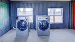 Een wasserij met twee voorlaadwasmachines, een houten plafond en een blauwe muur.