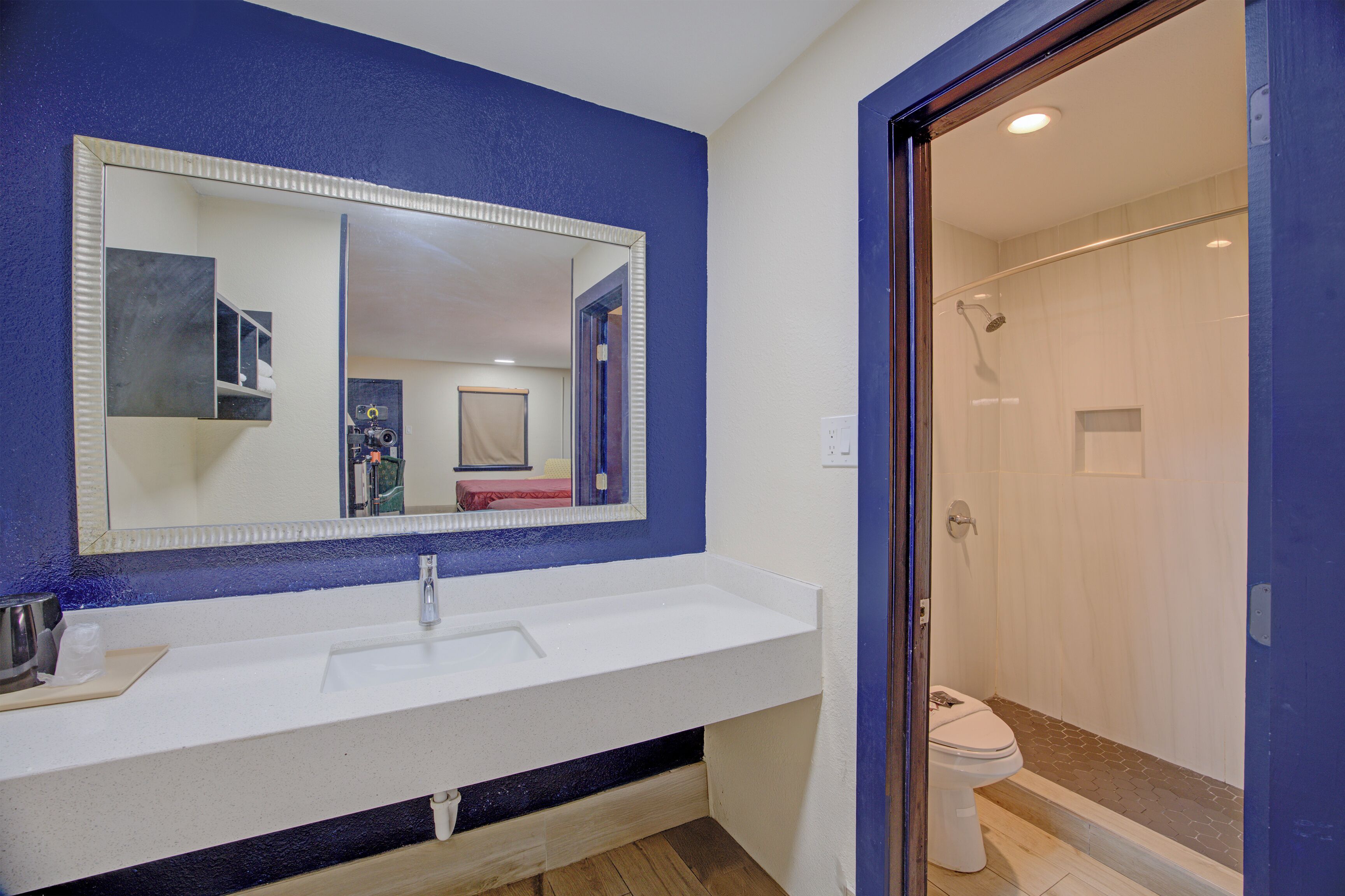 Un baño con un lavabo blanco, un espejo grande y una zona de ducha.
