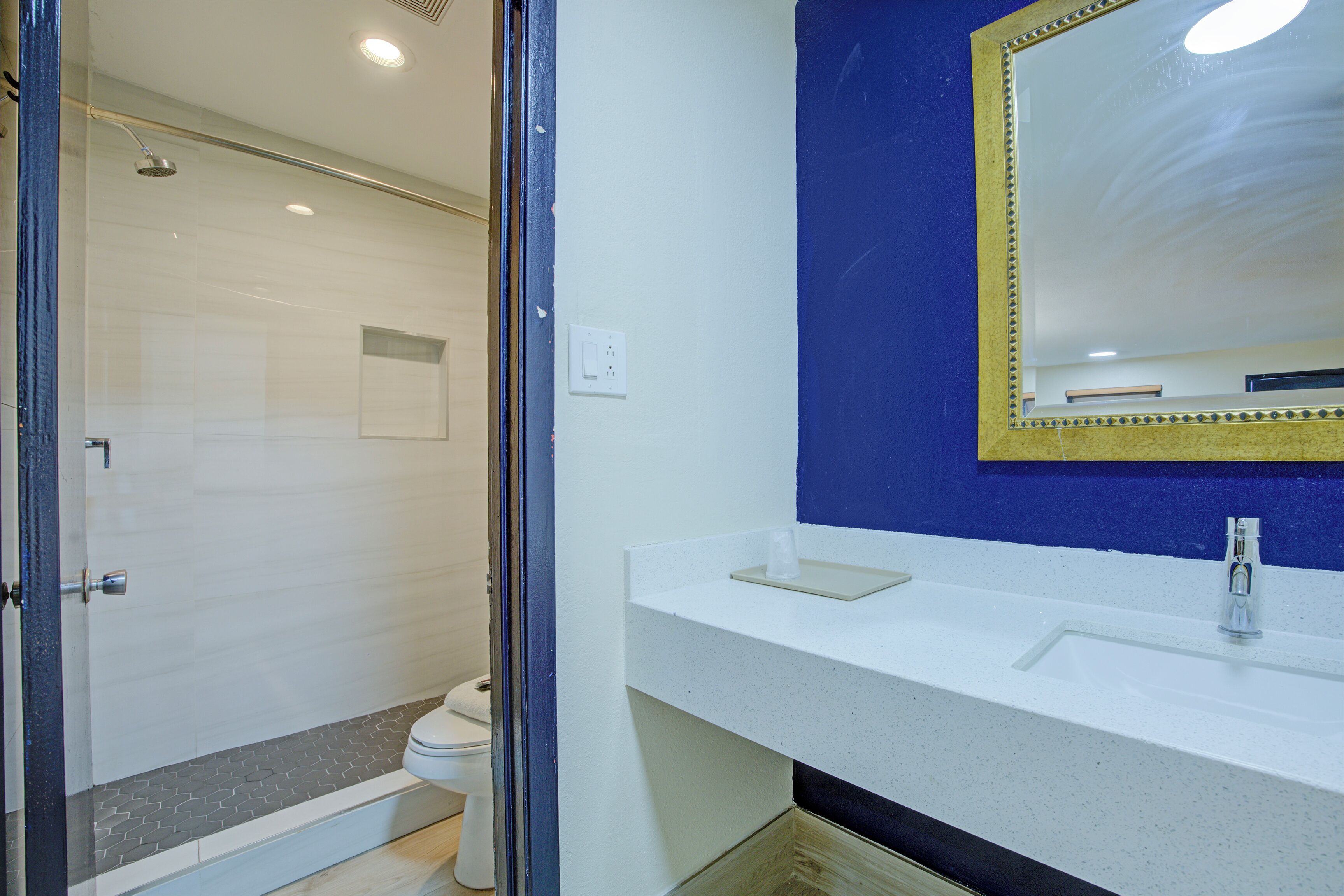 A bathroom with a shower, toilet, sink, and mirror.