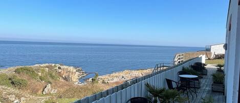 A wooden deck with outdoor seating and a view of the ocean.