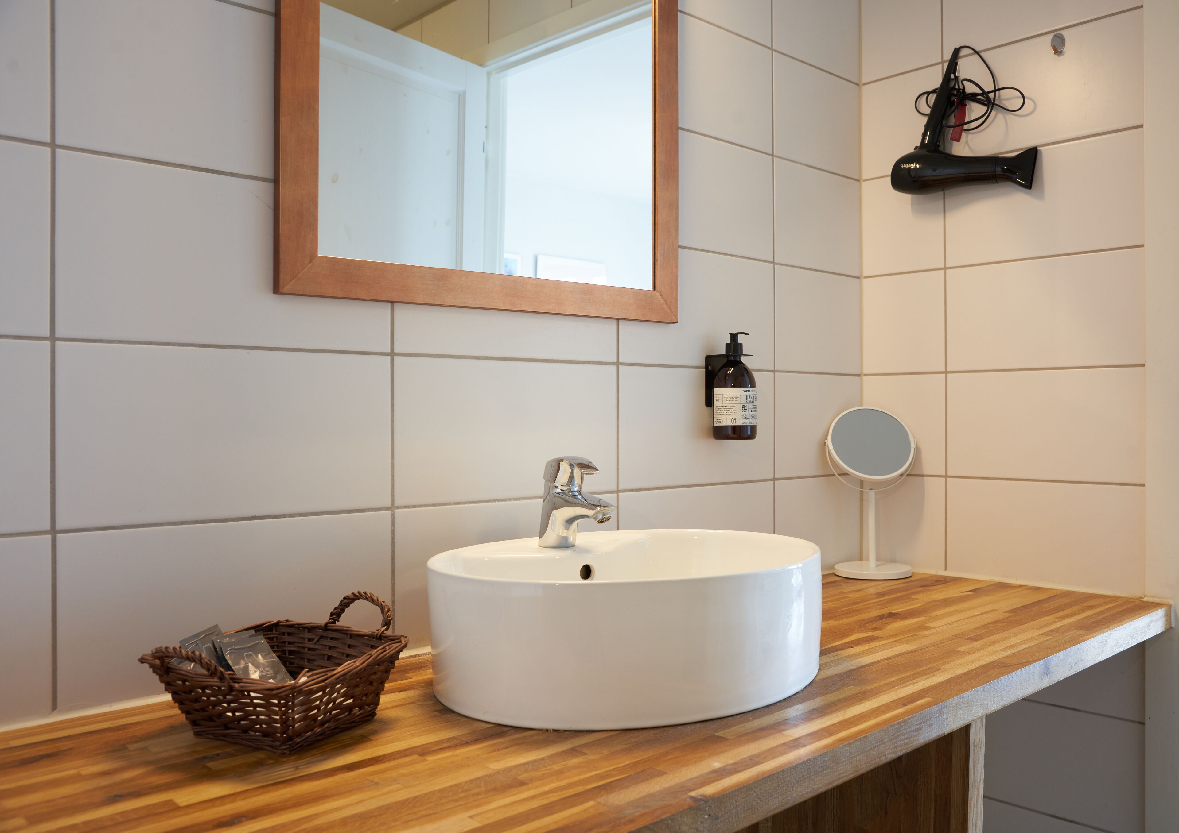 A bathroom with a white sink, wooden countertop, and a mirror.