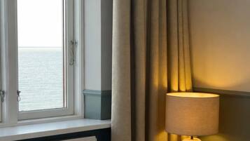 Una habitación de hotel con una cama, una ventana con cortinas y una lámpara de noche.