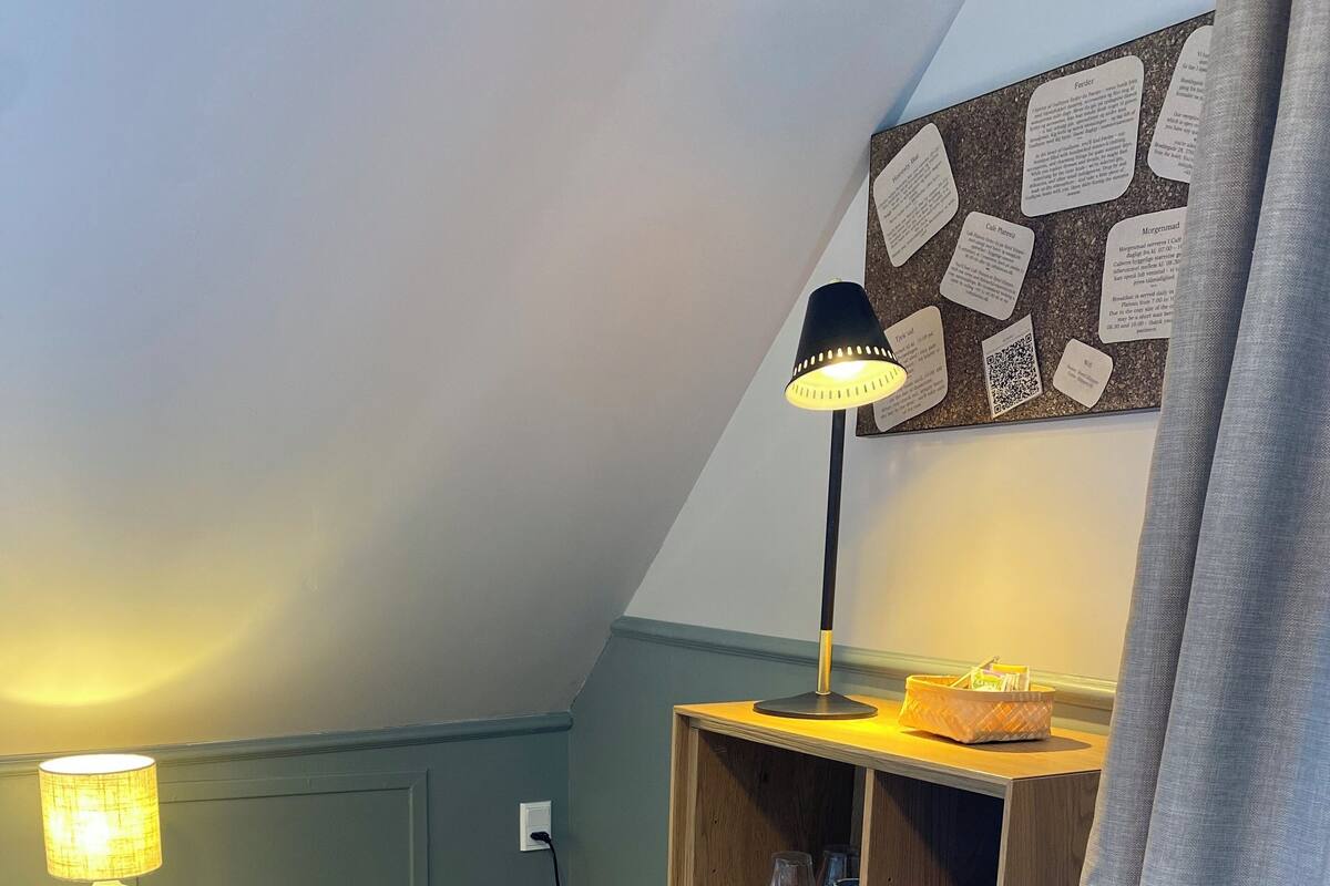 A cozy room with a bed, a lamp, a bulletin board, and a wooden shelf with storage baskets.