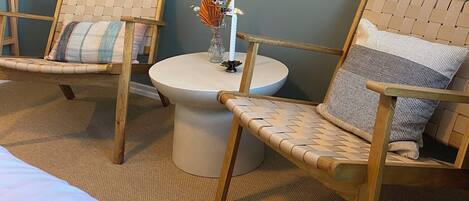 A room with two wicker chairs, a small round table with a candle, and a hanging light fixture.