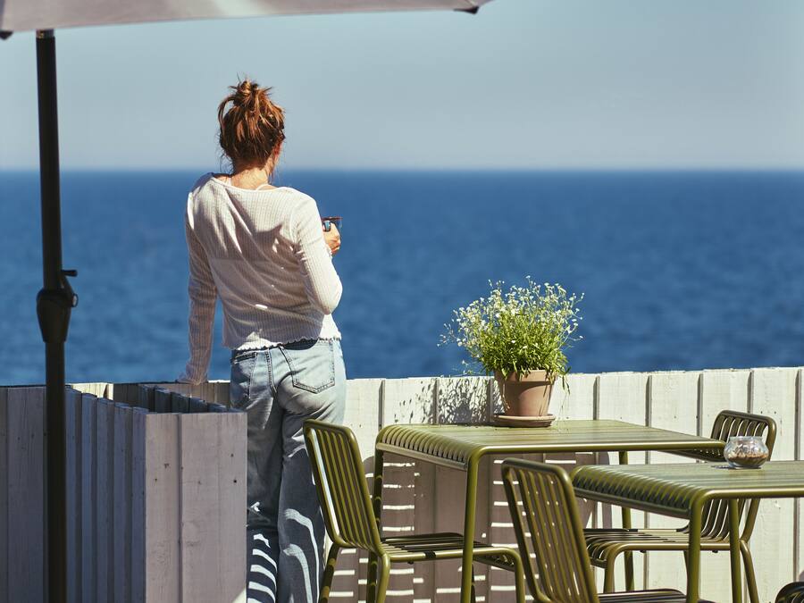 Une personne se tient debout près d’une table, avec vue sur l’océan.