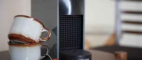 A coffee maker, a mug, and a thermos on a table.