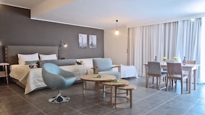 A modern hotel room with a bed, a sofa, a dining table, and chairs. - Amphitryon City Hotel (Rhodes)