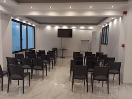 Egy konferenciaterem, sorokban elrendezett székekkel, egy nagy képernyővel és egy projektorral.
