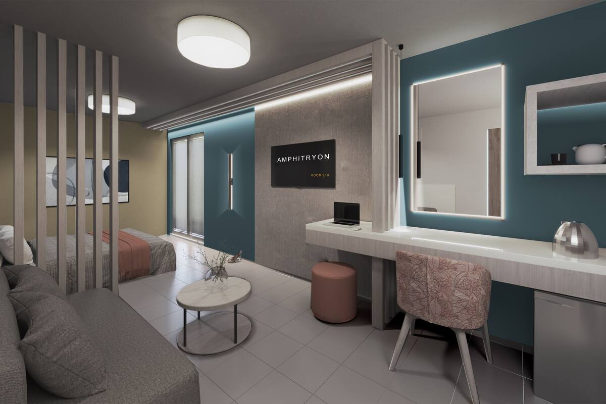 A modern room with a sofa, a small round table, a mirror, and a laptop on a desk.
