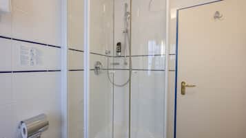 A glass-enclosed shower with a handheld showerhead and a wall-mounted control panel.