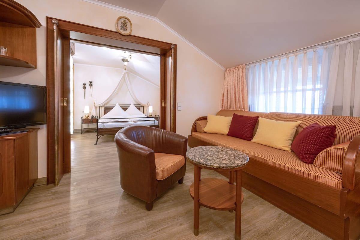 Una sala de estar moderna con sofá, sillón y una mesita. Un televisor está montado en la pared.