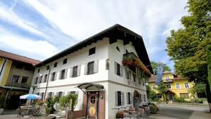 A traditional European building with a courtyard, a covered entrance, and outdoor seating. - Hotel Neuwirt (Sauerlach)