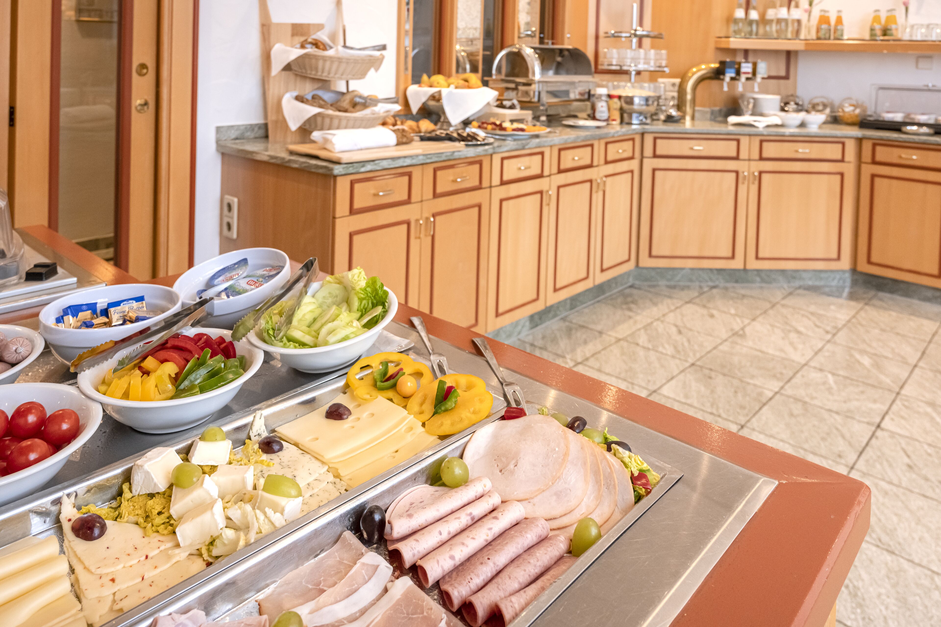 A buffet with various food items including meats, cheeses, and vegetables.