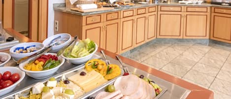 A buffet with various food items including meats, cheeses, and vegetables.