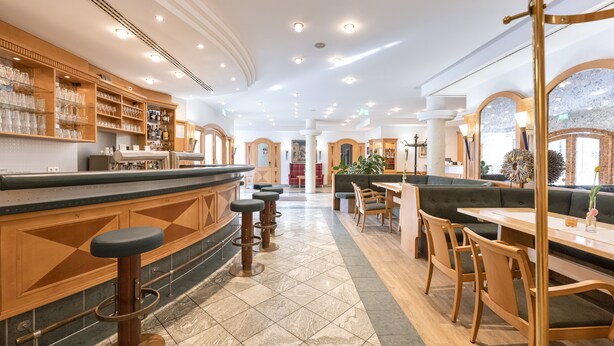 A spacious hotel lobby with a bar area, seating arrangements, and a view of the outdoors. - Hotel Neuwirt (Sauerlach)