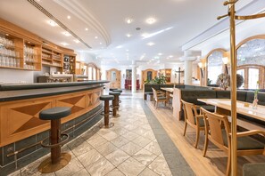 Un amplio vestíbulo de hotel con zona de bar, asientos y vistas al exterior.