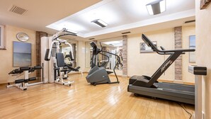 A gym with various exercise equipment, including treadmills and weight machines, on a wooden floor. - Hotel Neuwirt (Sauerlach)
