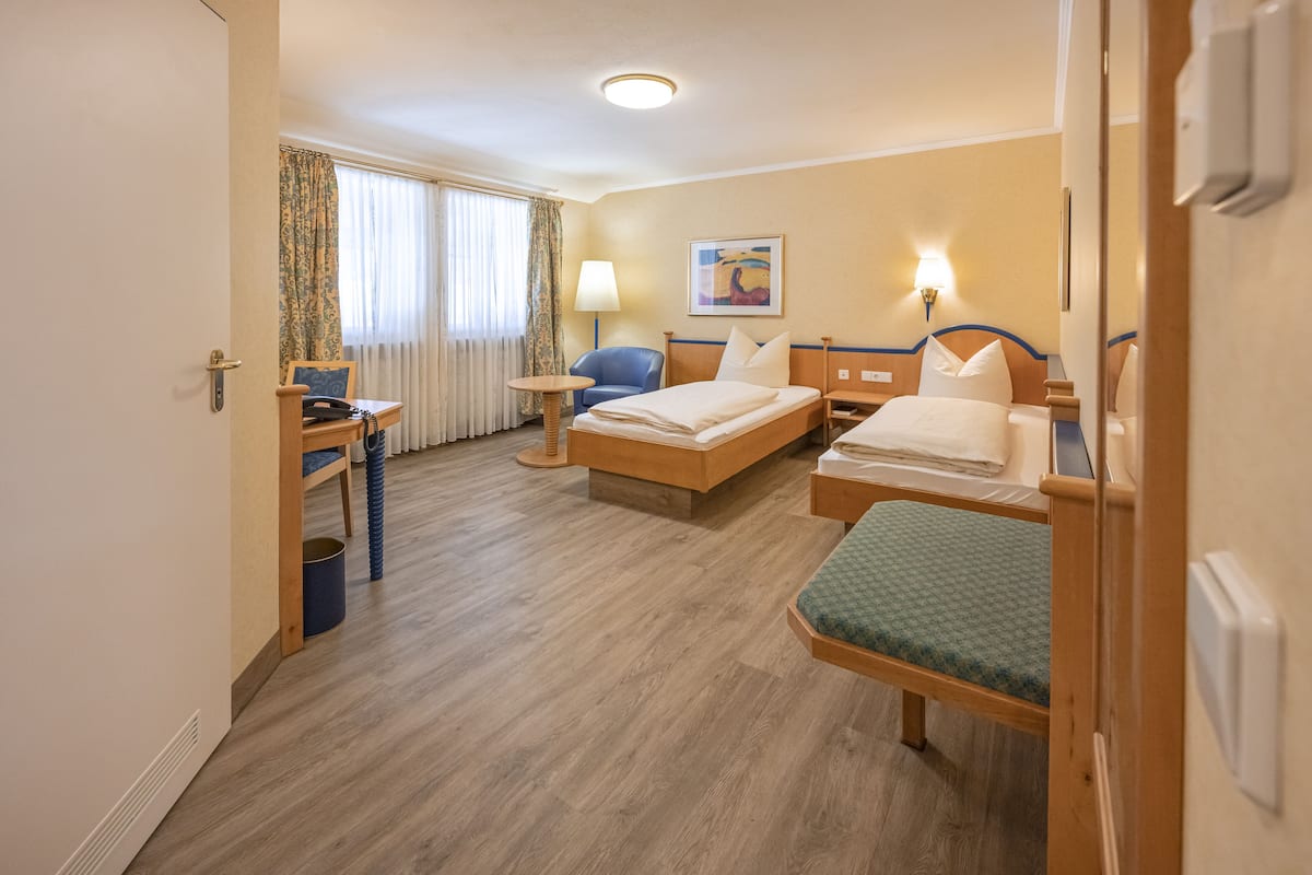 Habitación de hotel con dos camas, un escritorio, una silla, una lámpara y un cuadro en la pared.