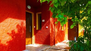 A red building with two wooden doors, a tiled entrance, and a potted plant. - Katerini Hotel Apartments (Rethymno)