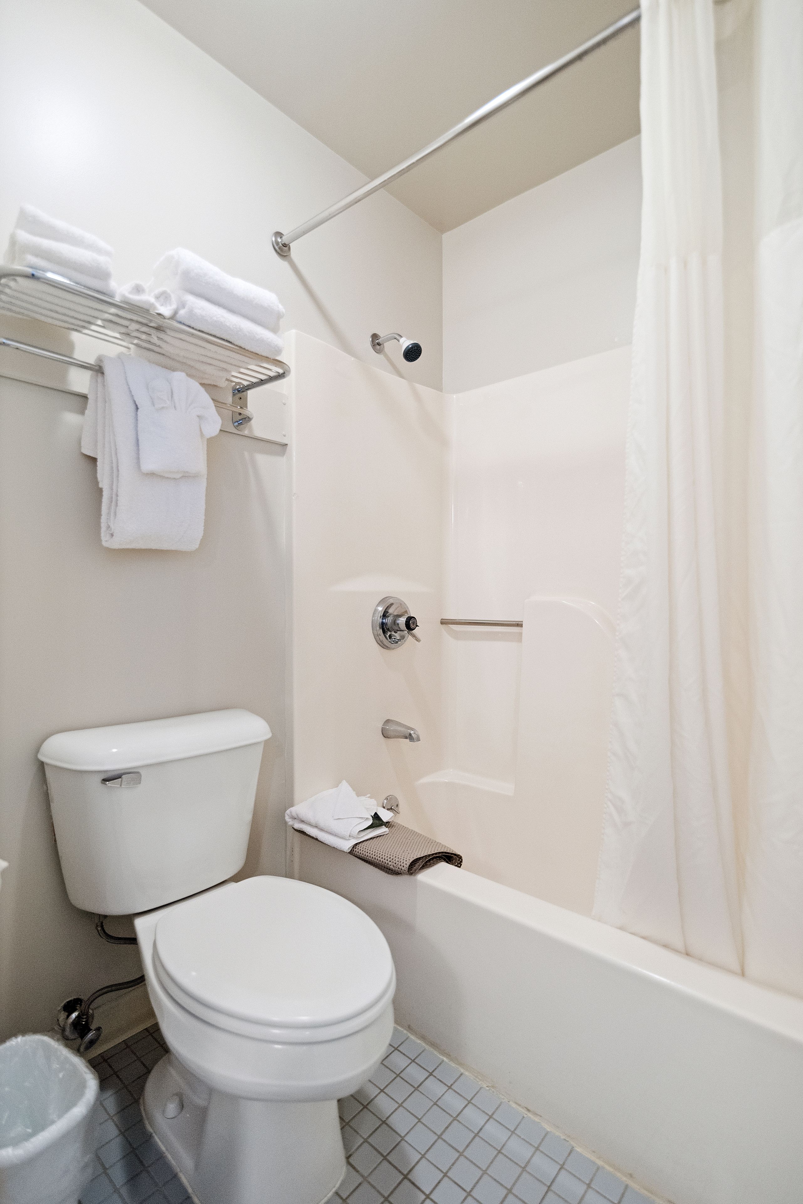 Une salle de bain comprenant des toilettes, une douche avec un rideau et un porte-serviettes avec des serviettes pliées.