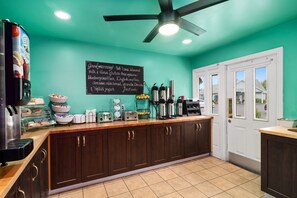 A kitchen with teal walls, a blackboard menu, and a coffee station.